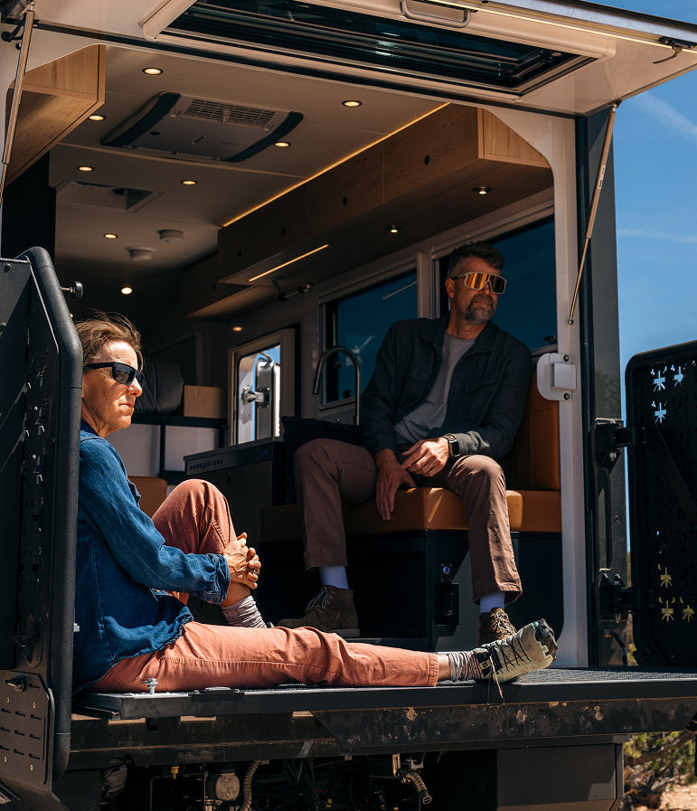 Two people sitting inside a vehicle with an open door, enjoying the outdoors.