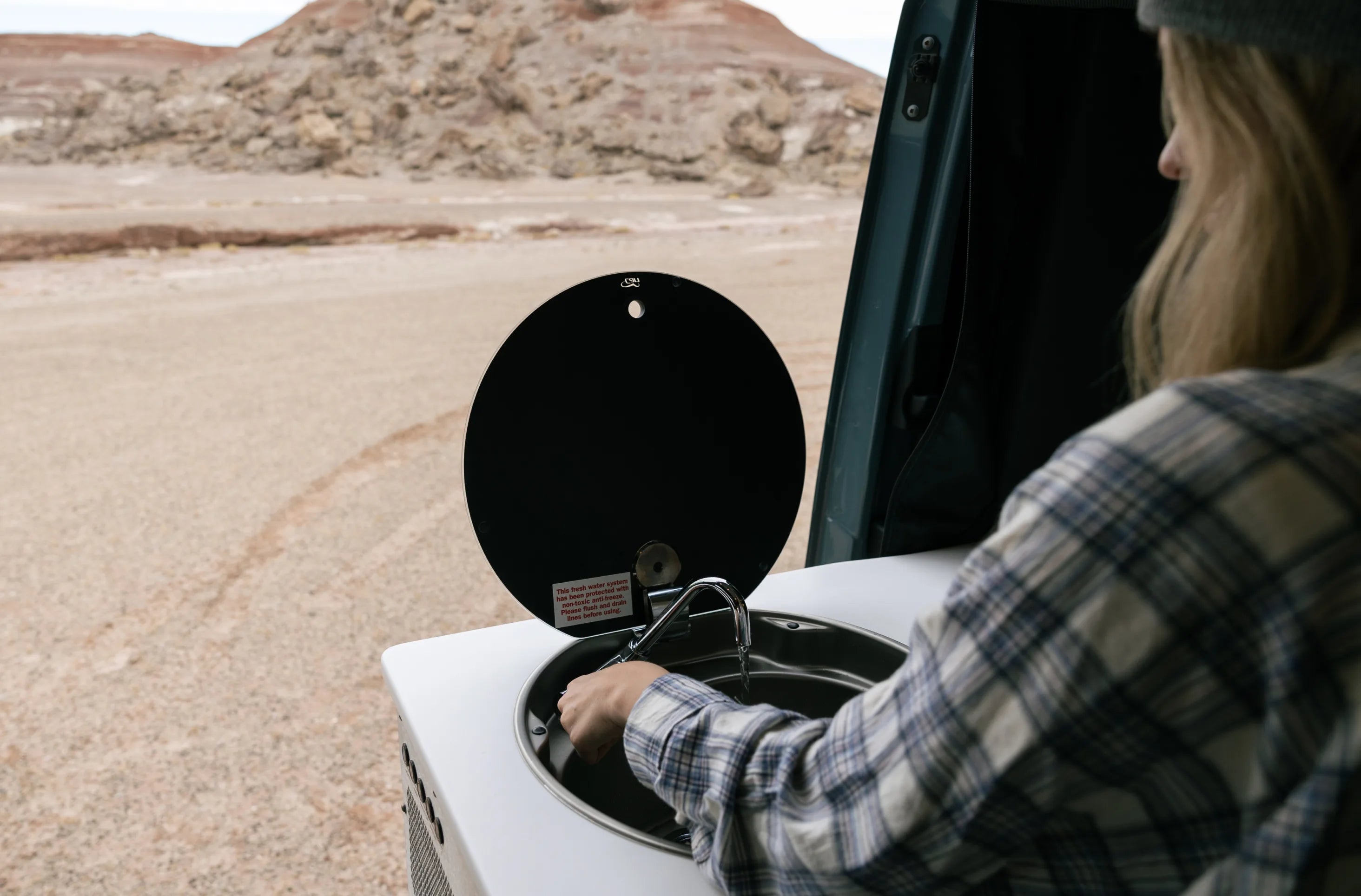 Camper van sink interior with person using faucet, ideal for overland adventure travel