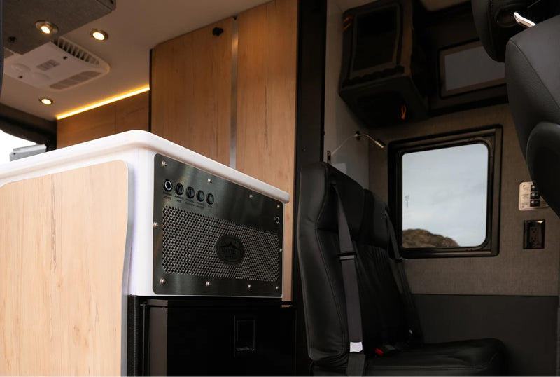 Modern camper van interior with modular seating, wood cabinetry, and control panel, ideal for van life, overlanding, and adventure travel.