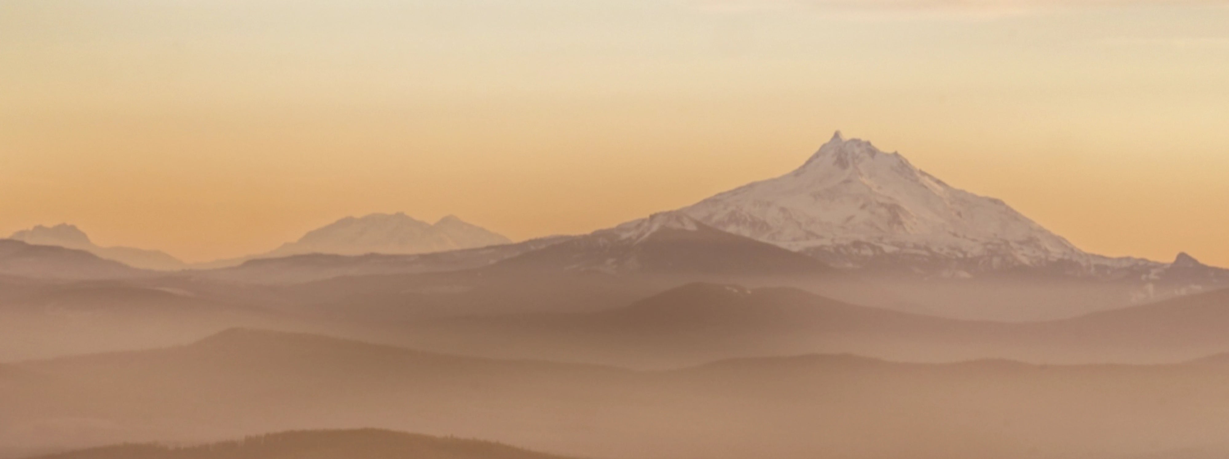 Snow-capped mountain range at sunrise, ideal for overland, expedition, vanlife adventure travel.