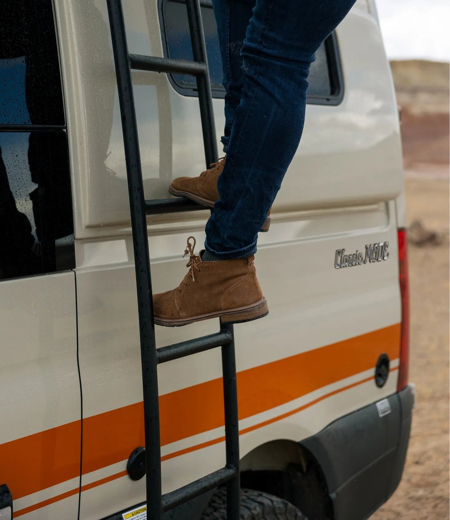 Person climbing exterior ladder on Classic MODE camper van, adventure van, overland vehicle