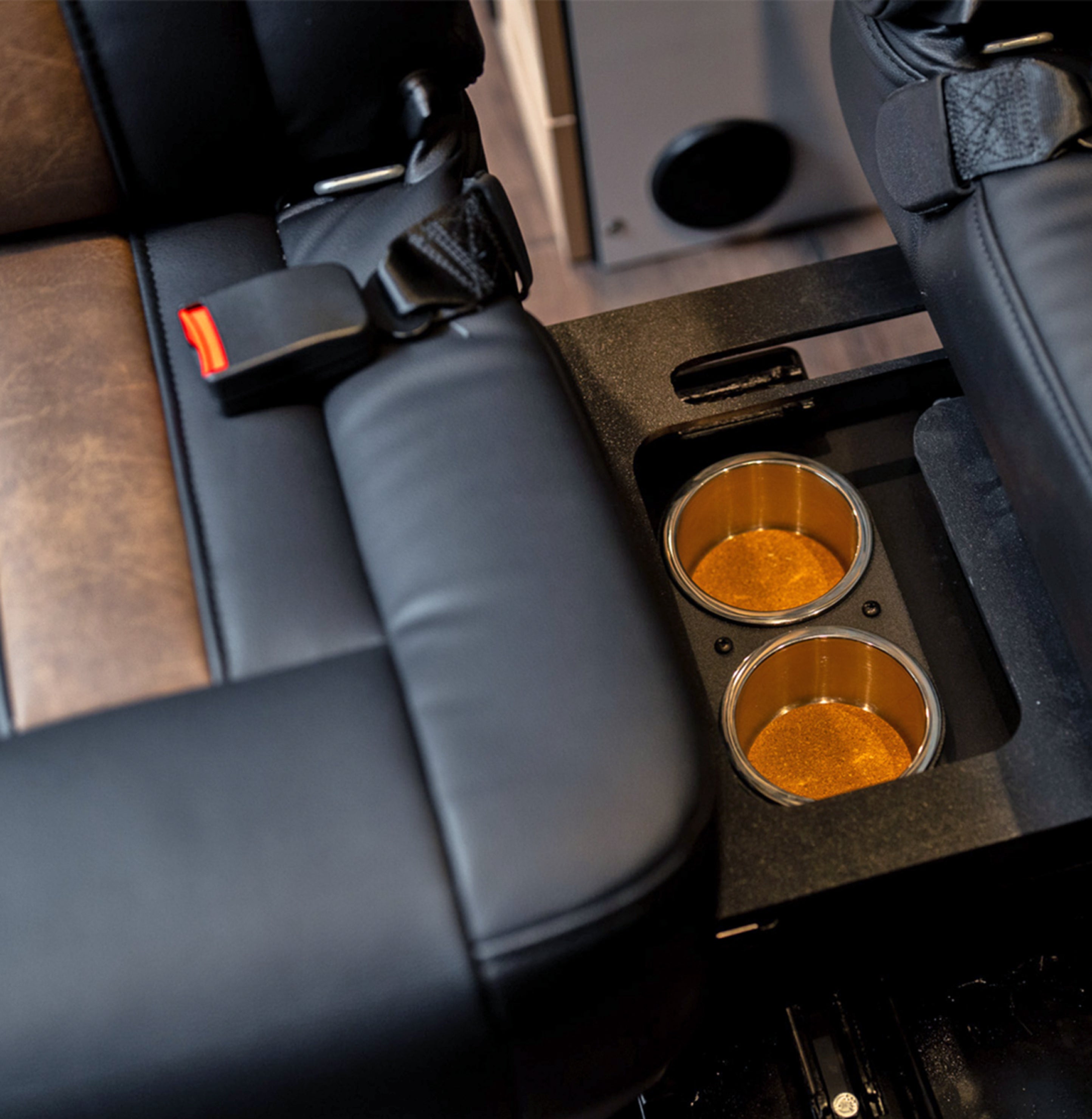 Cup holders between black leather camper van seats, ideal for adventure van or vanlife travel.