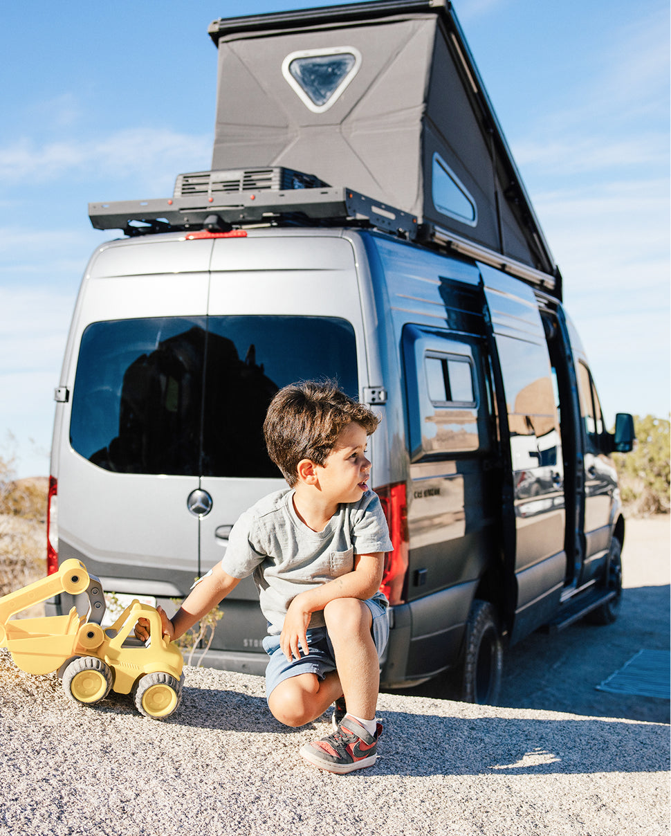 Child playing beside a pop top Sprinter campervan, ideal for overland adventure travel and vanlife