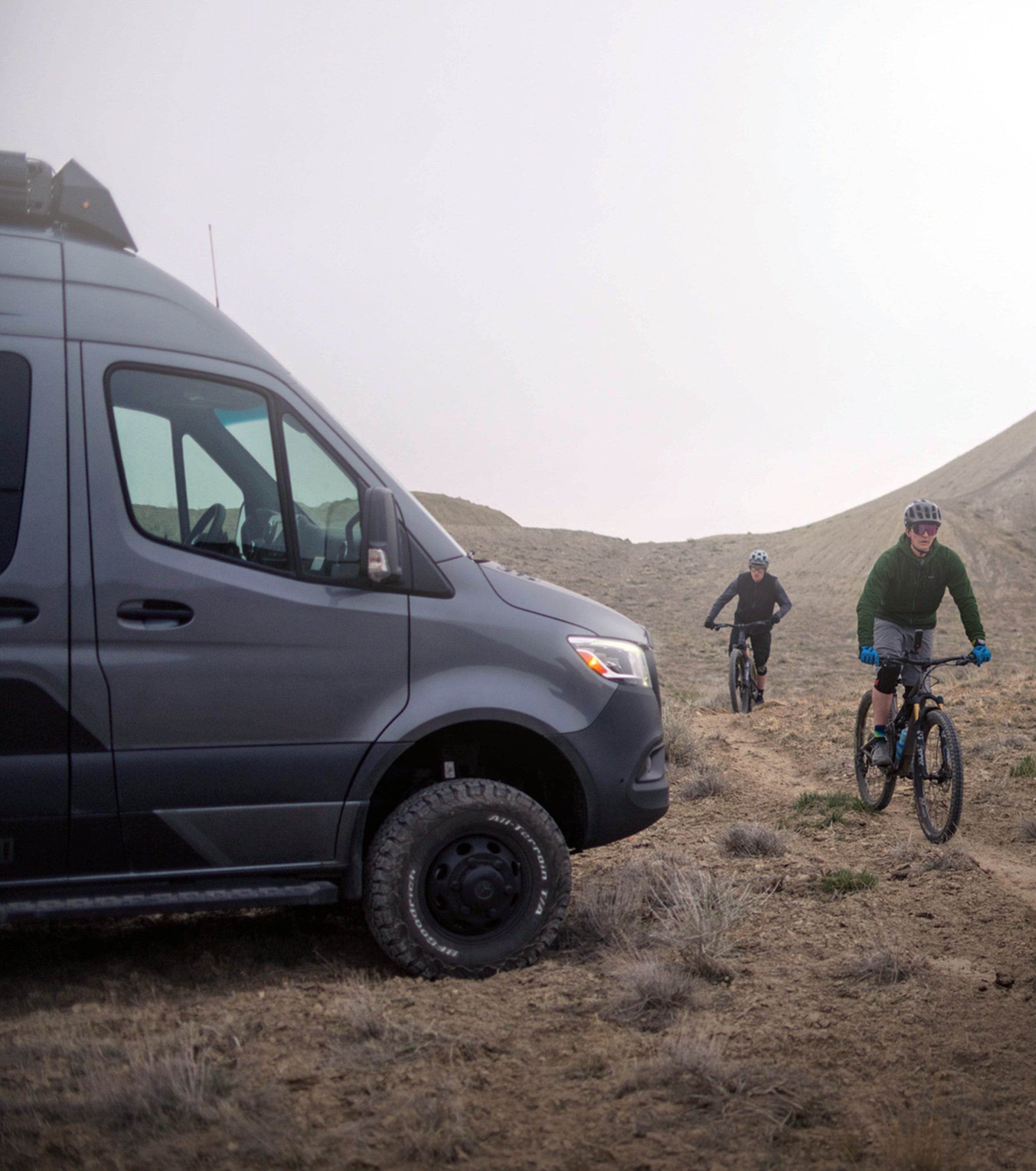 Sprinter 4x4 camper van and mountain bikers on rugged offroad trail, overlanding adventure