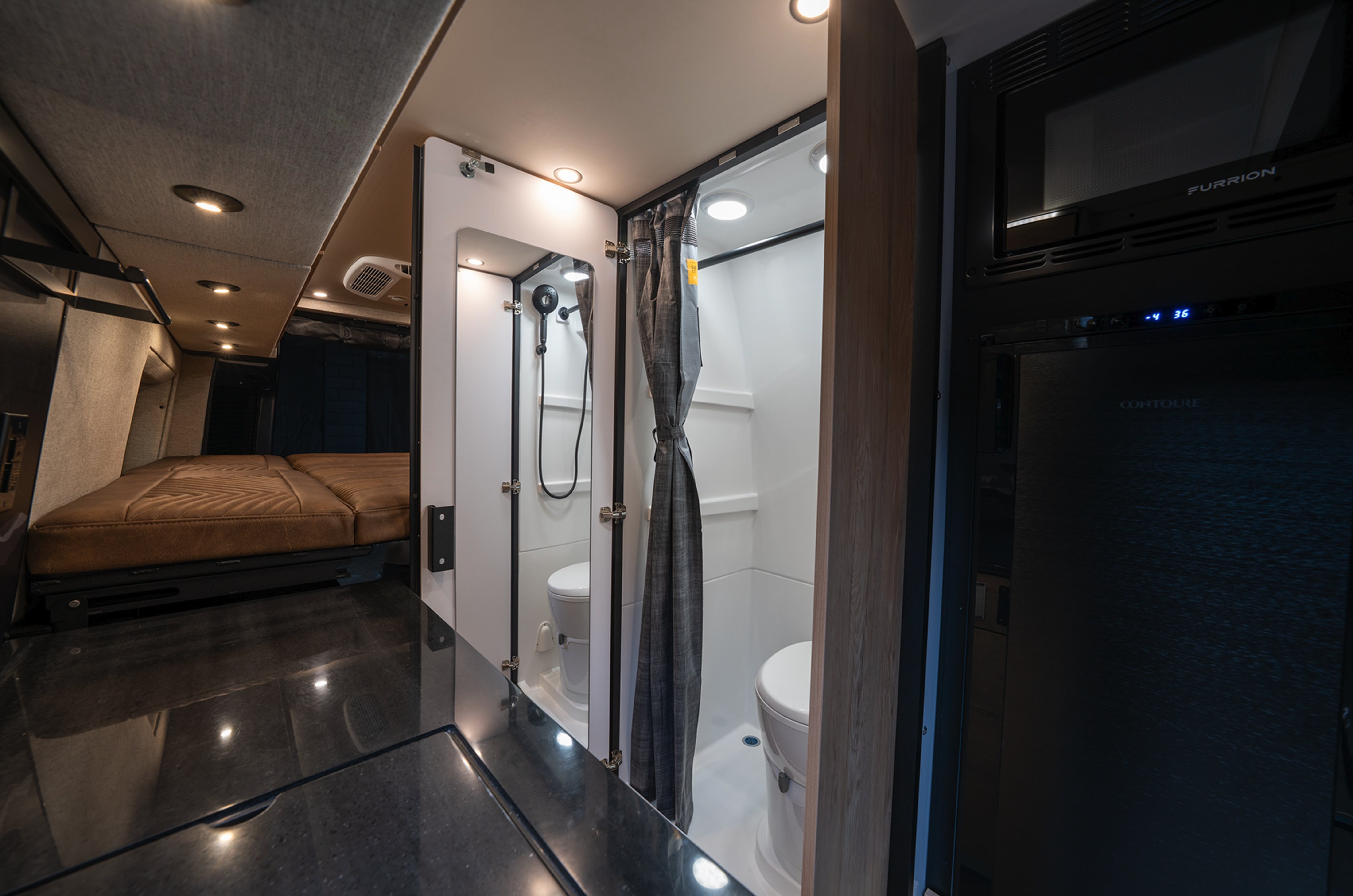 Modern camper van interior with wet bath, shower, toilet, bed, and kitchenette in adventure van