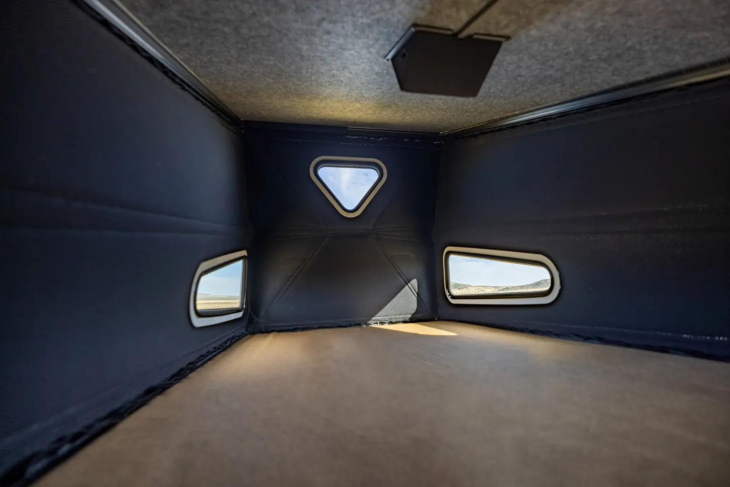 Interior sleeping loft with windows in a modern camper van, perfect for vanlife or overlanding adventures.