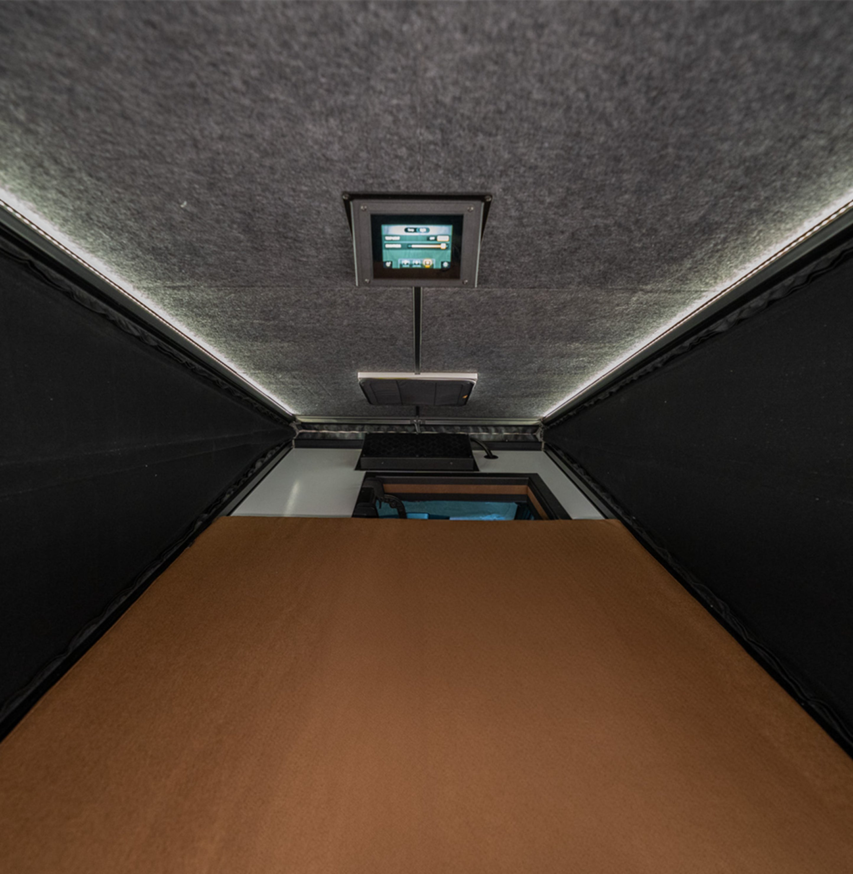 Camper van interior with modern control panel, ambient lighting and sleeping area, ideal for vanlife, overlanding or adventure van travel.