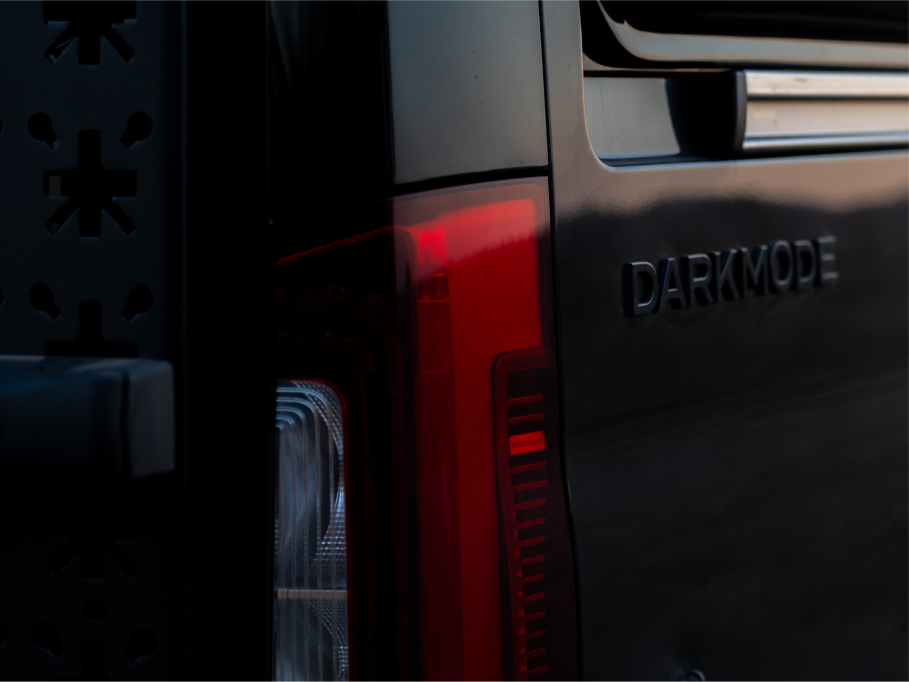 Closeup of taillight and Dark Mode badge on offroad adventure van, campervan, overland rig