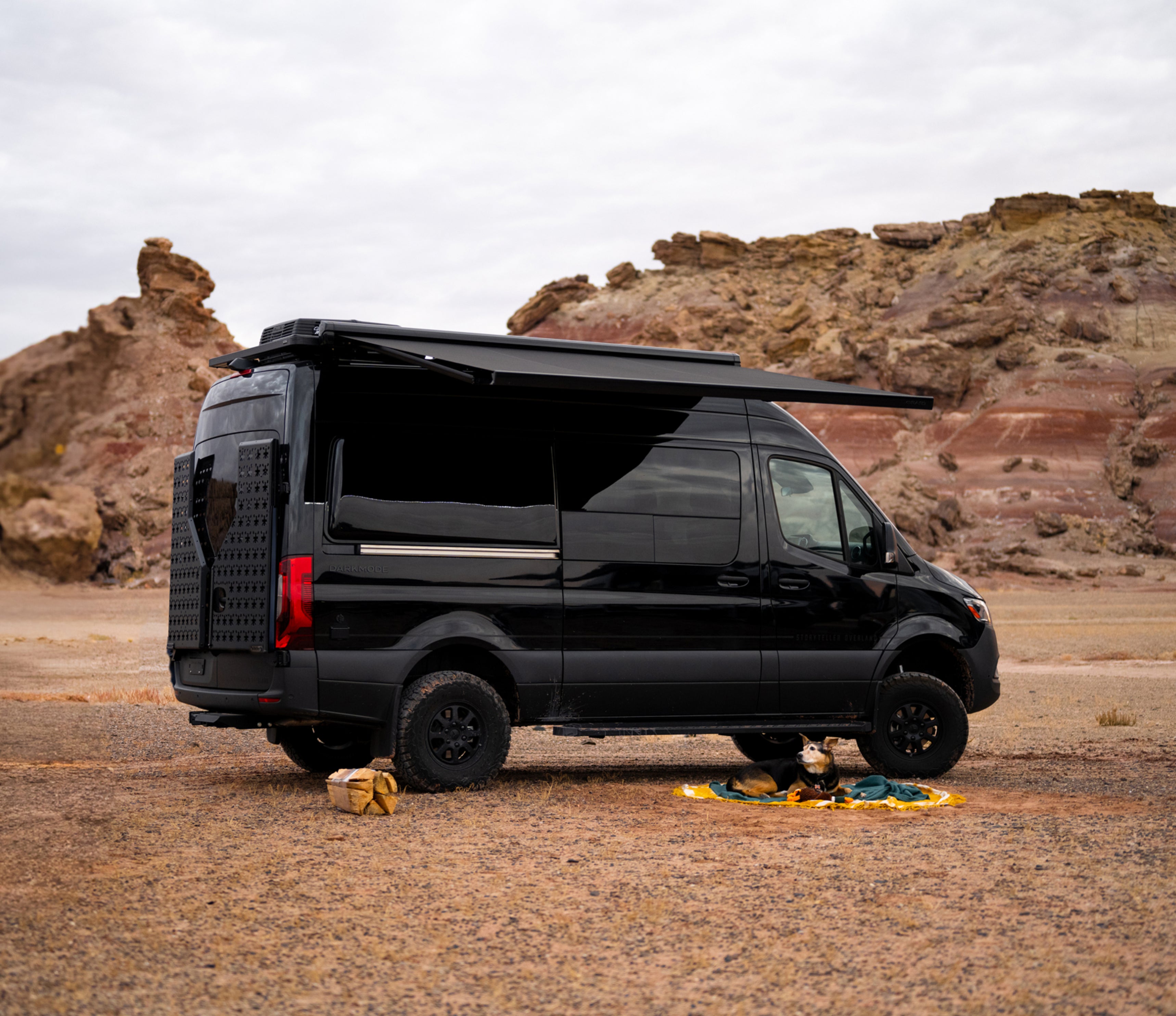 Black 4x4 adventure van with awning, camper van for offroad overlanding in rocky desert