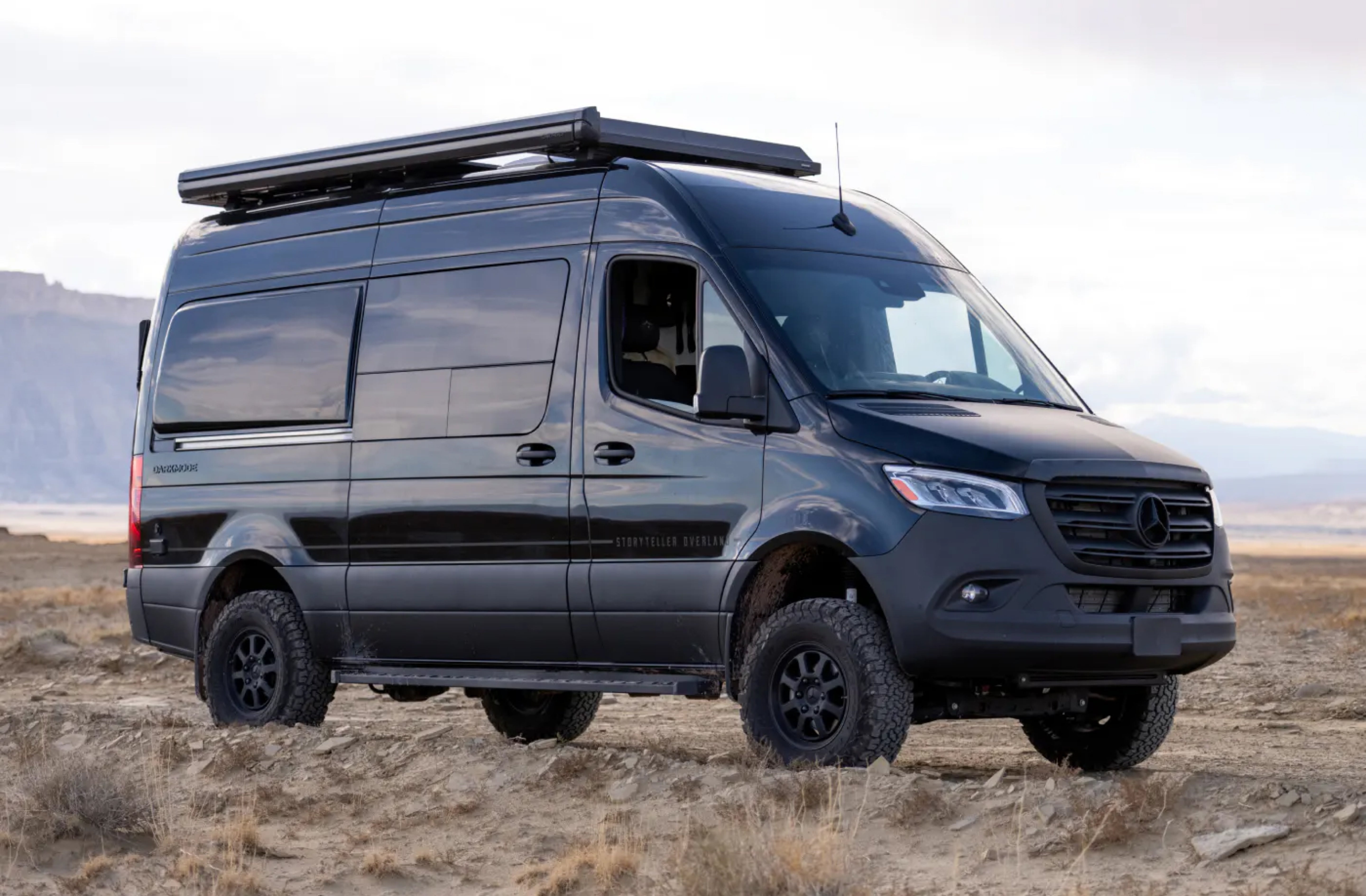 Black Sprinter 4x4 adventure van with off-road tires parked outdoors, ideal for overlanding, camper van travel and vanlife.