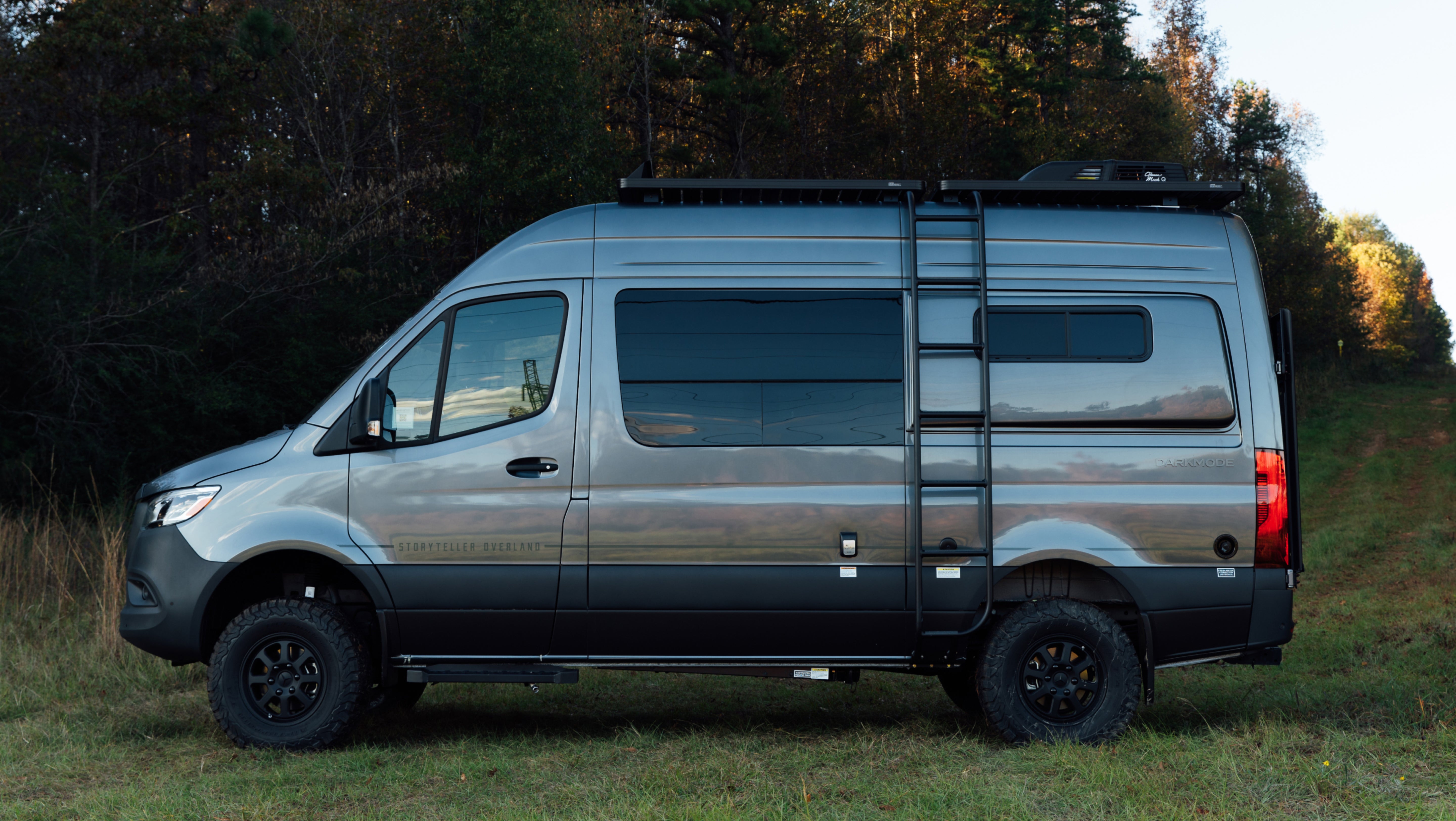 Dark grey Sprinter 4x4 camper van with offroad tires and ladder, ideal for overland adventure travel