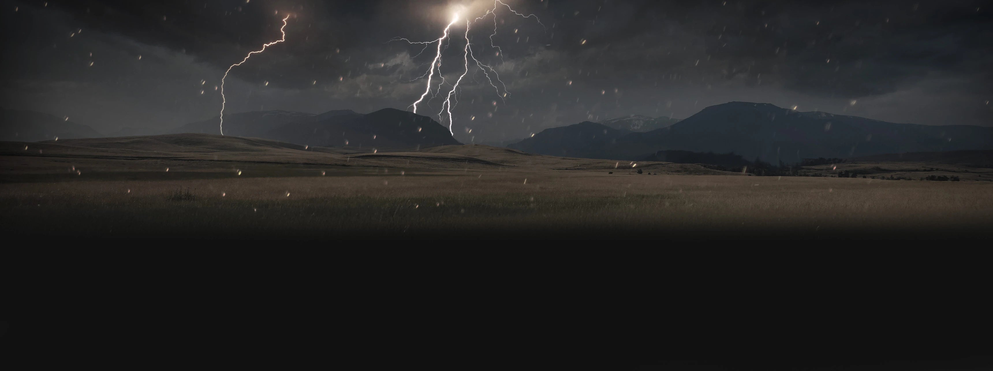 Mountain field with dark storm clouds, lightning and rain, ideal for overlanding adventure travel