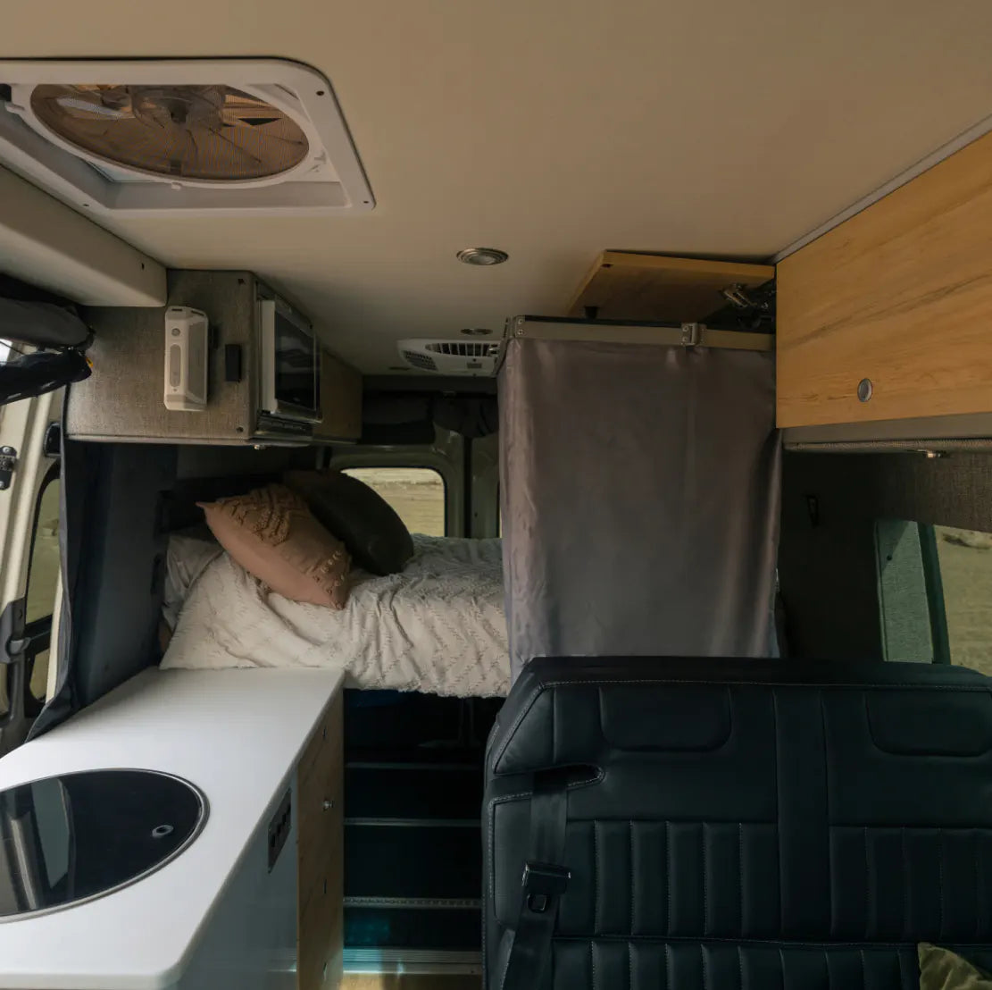 Camper van interior with bed, kitchenette, storage, and overland adventure van features