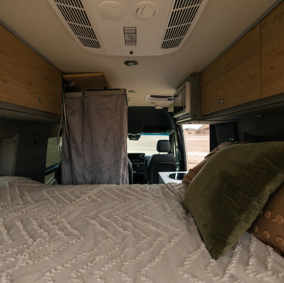 Camper van interior with bed, shower, cabinets, ideal for vanlife, road trip, overlanding.