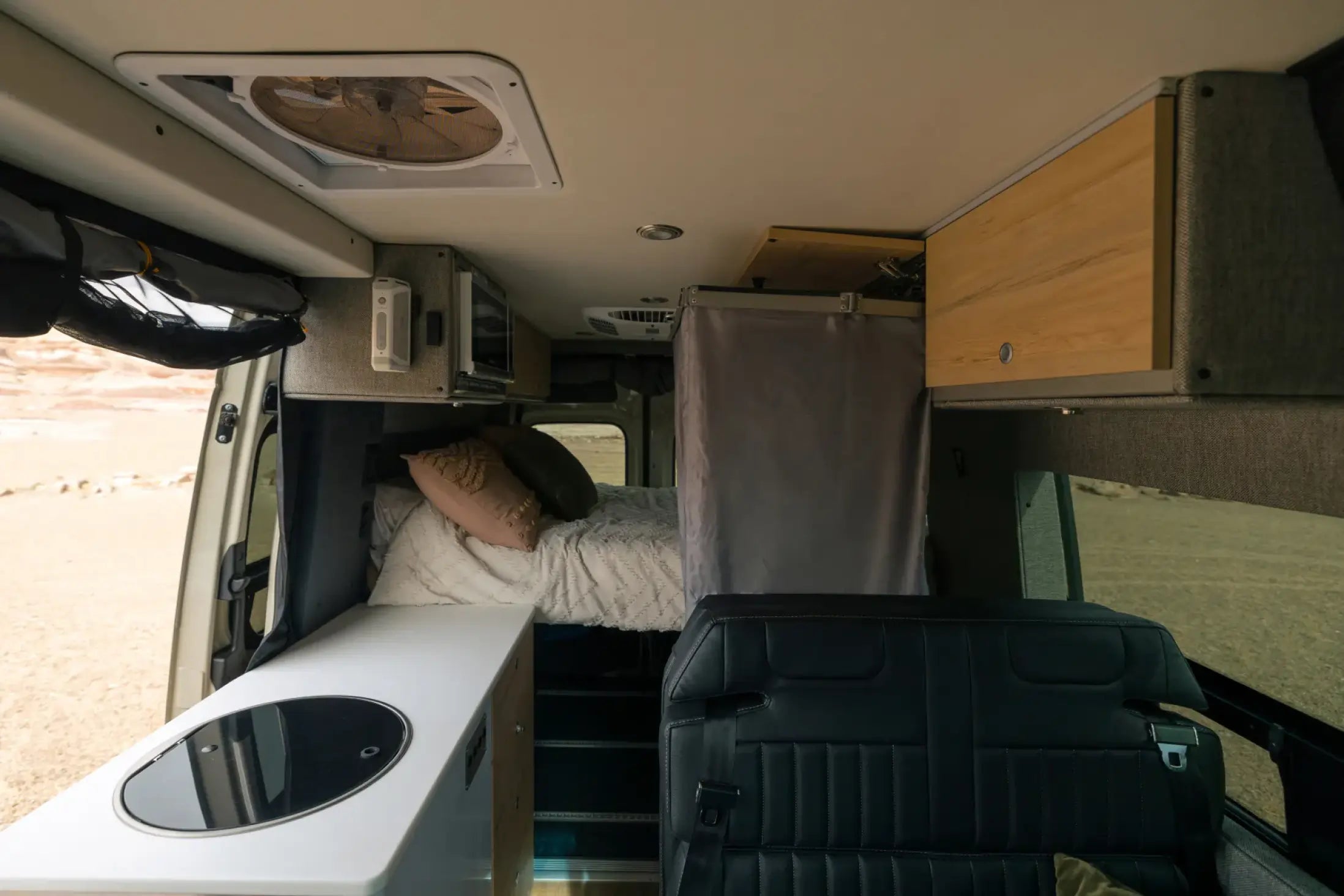 Modern camper van interior with bed, kitchenette, storage cabinets and leather seating, ideal for vanlife, adventure van, or overlanding.