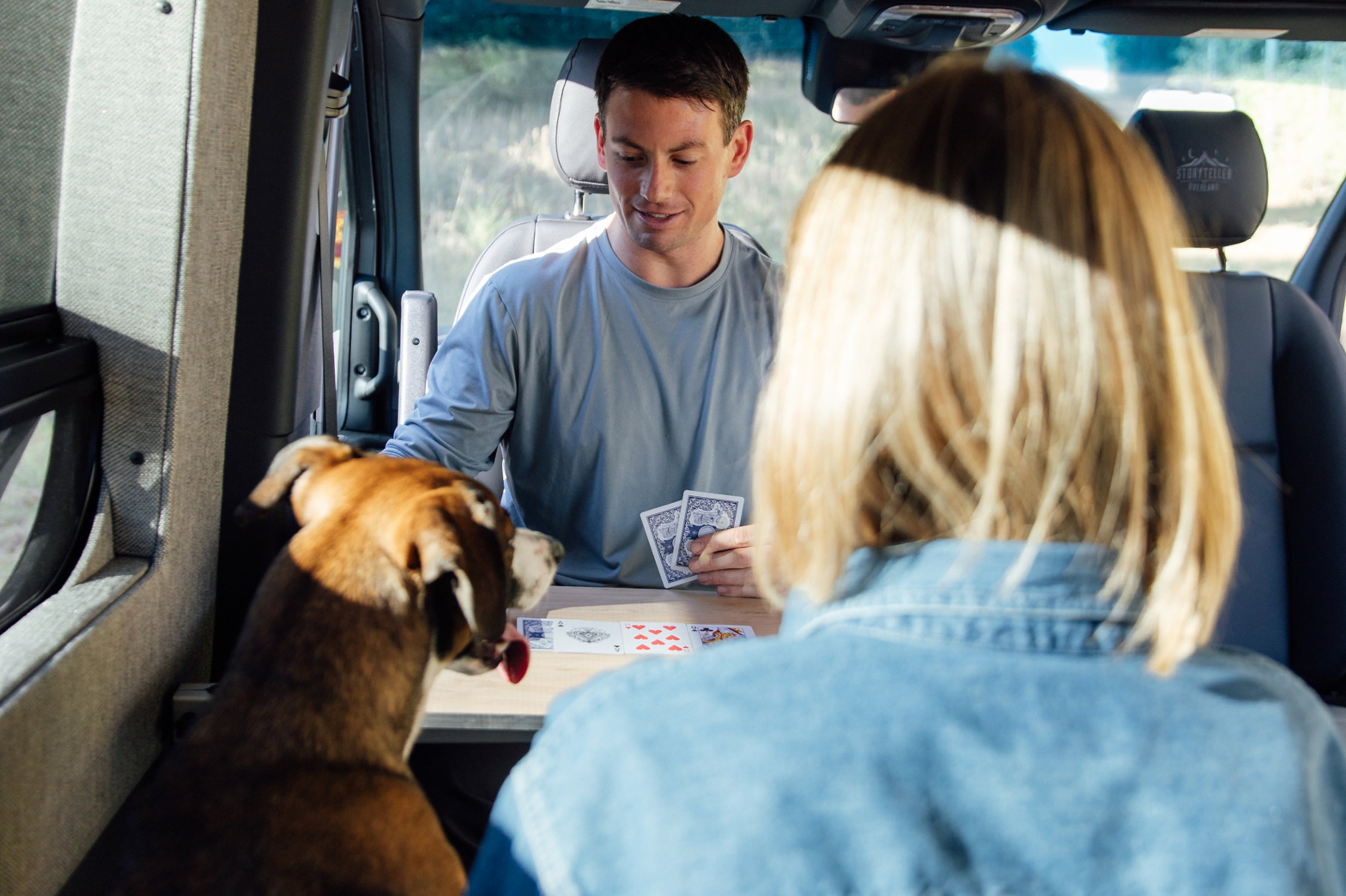 People and dog playing cards inside camper van, enjoying vanlife and adventure travel.