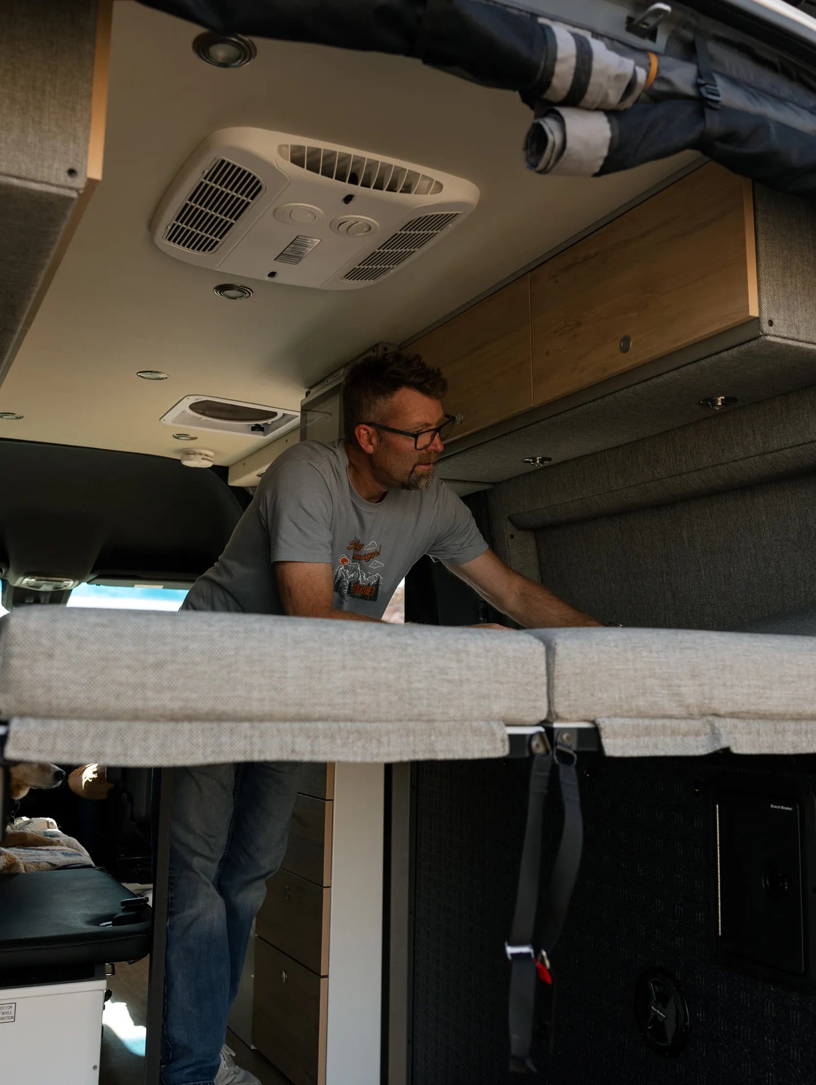 Man inside modern campervan setting up bed, showing Class B RV van life interior for adventure travel.