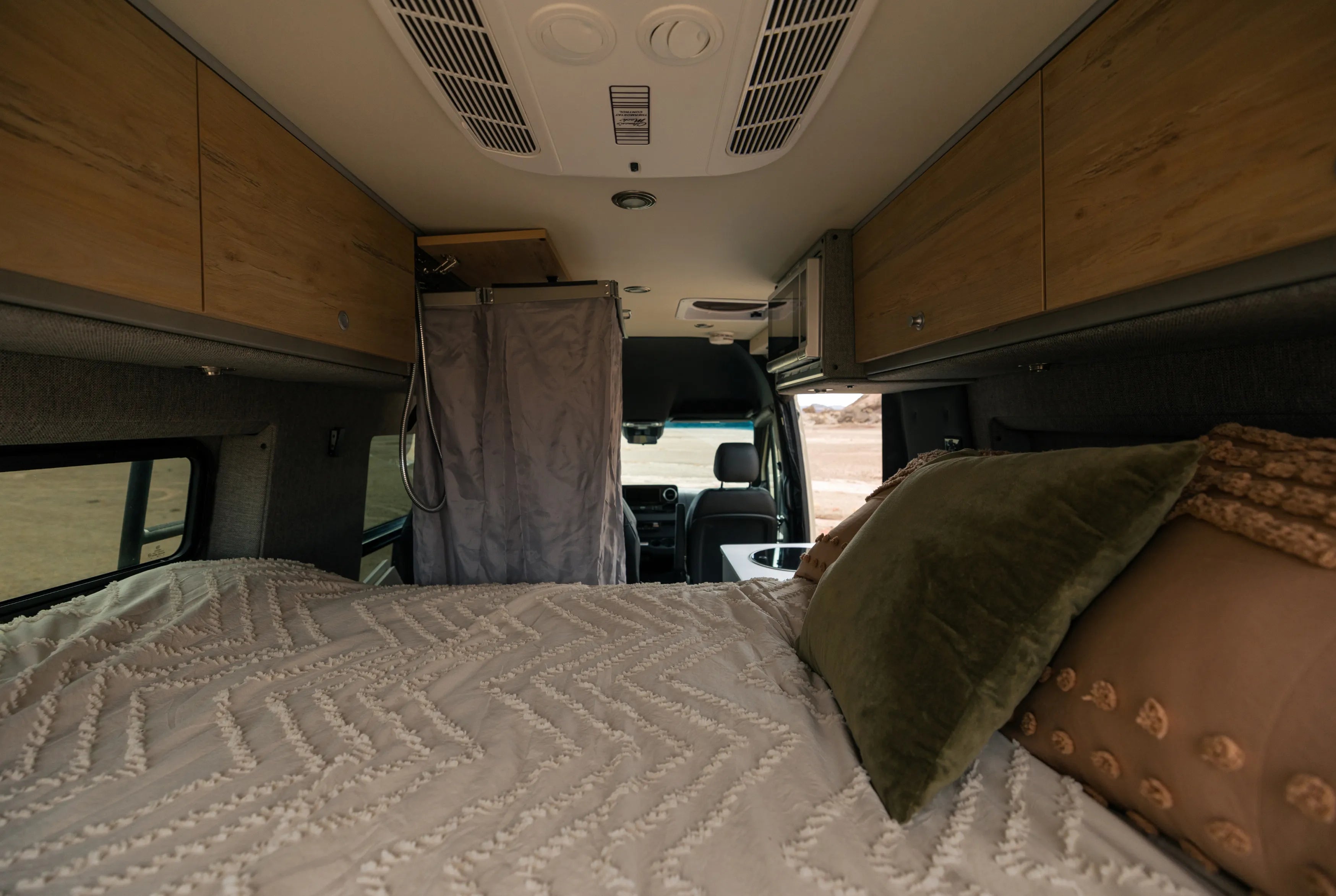 Interior bed of adventure van with overhead cabinets, ideal for campervan vanlife and overlanding