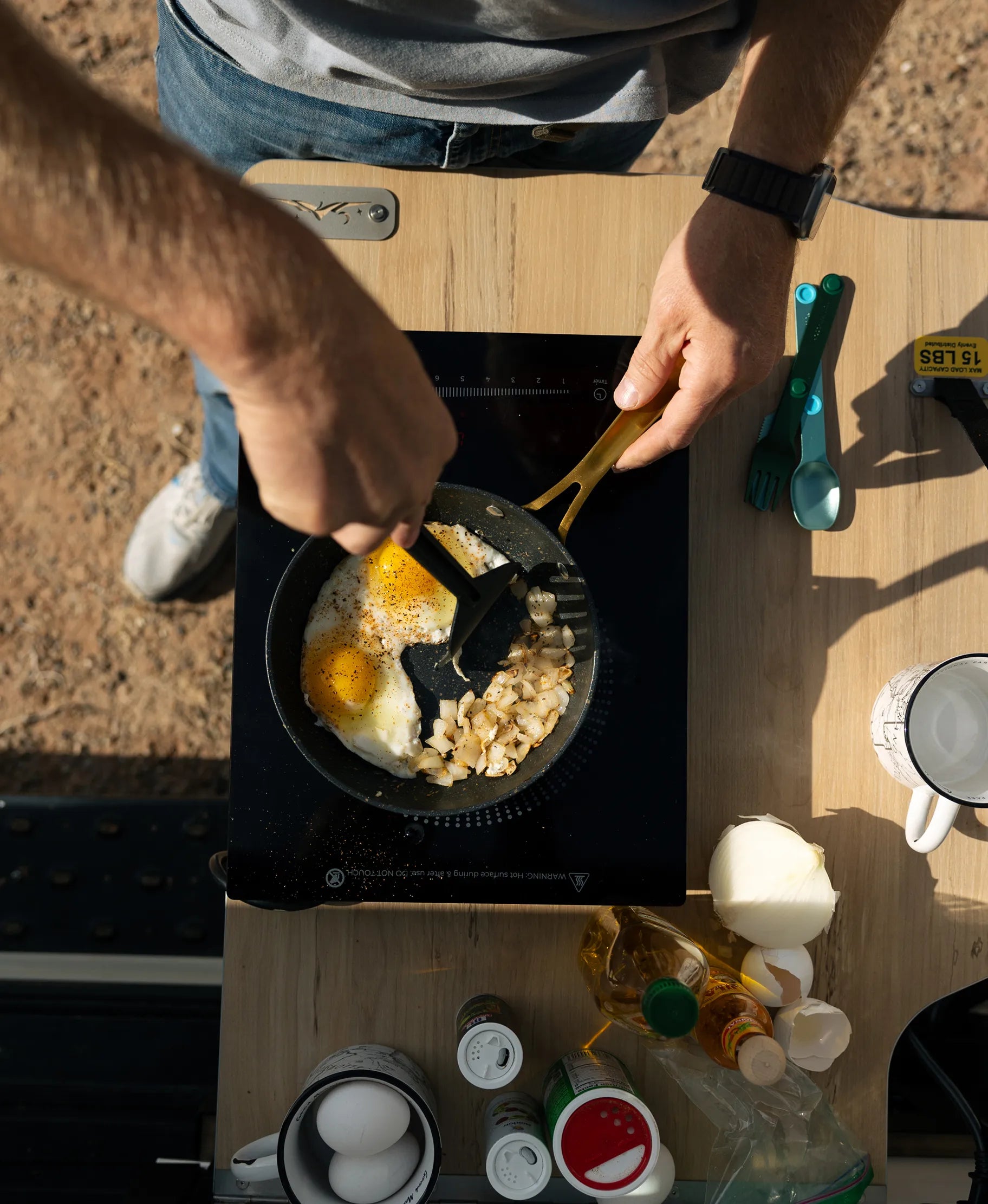 Cooking eggs and onions on an induction stove in a camper van, adventure van lifestyle