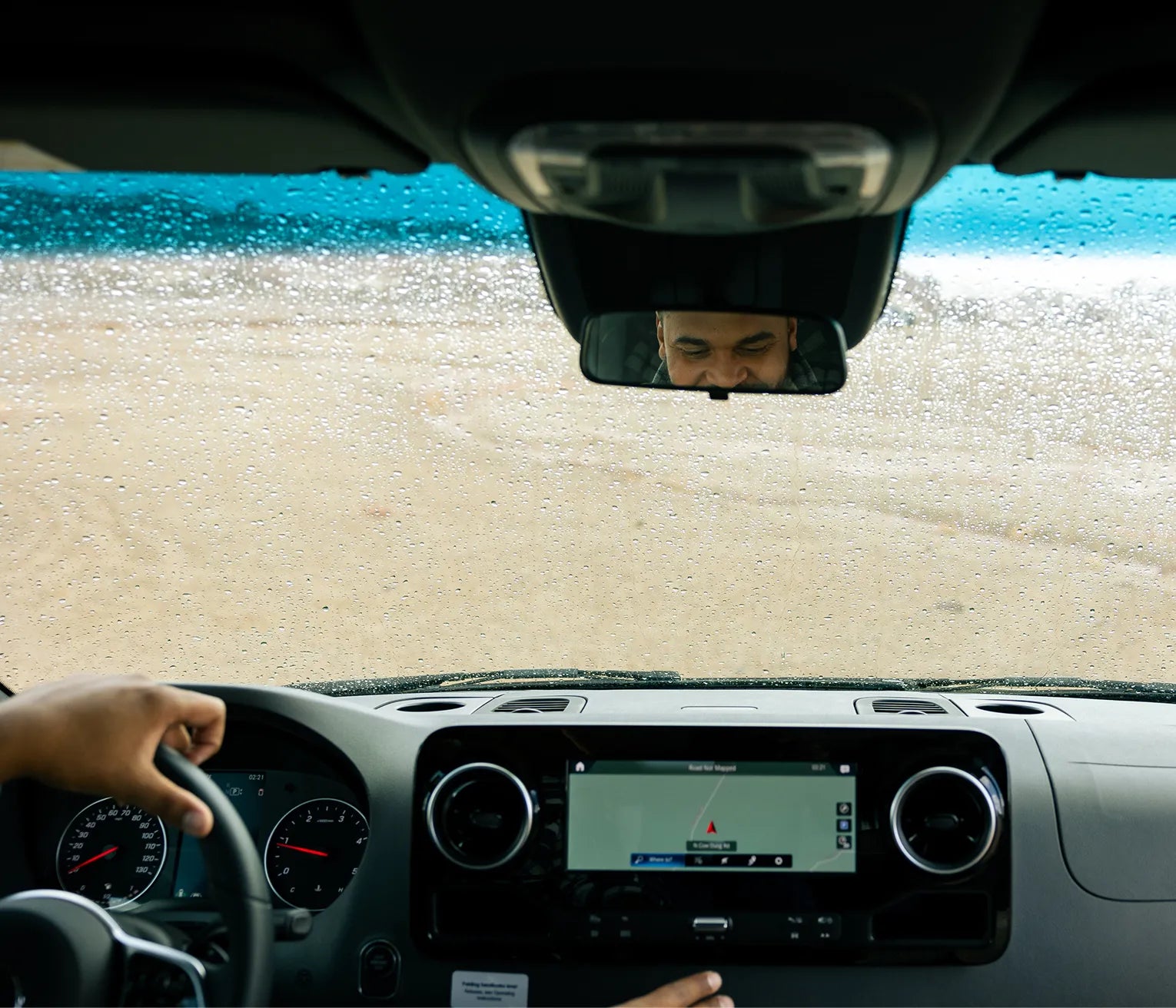 Camper van dashboard interior with navigation, steering wheel, and rainy windshield, perfect for vanlife, overlanding, and road trip adventure.