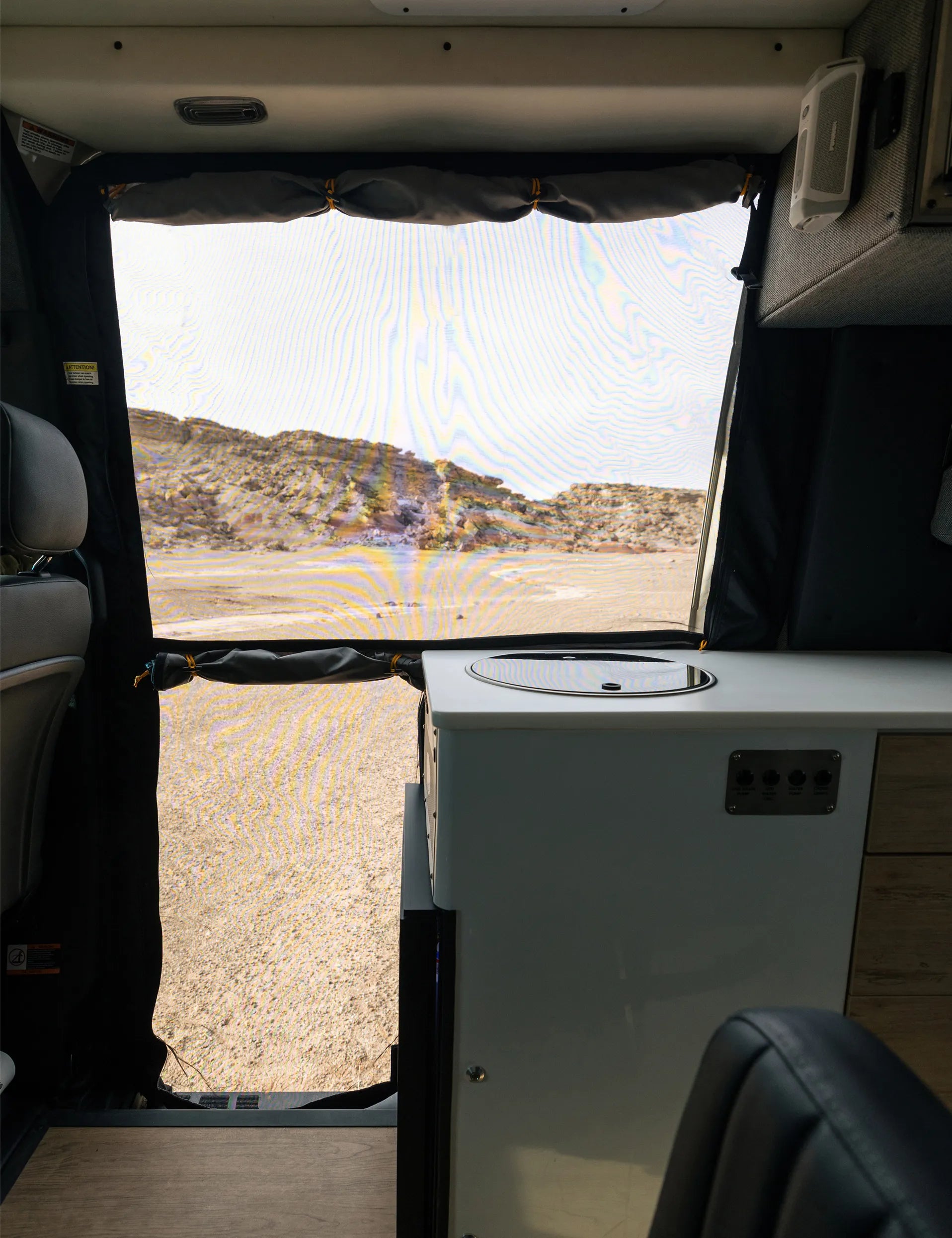 Interior of adventure camper van with kitchenette facing open desert landscape, perfect for vanlife and overlanding.