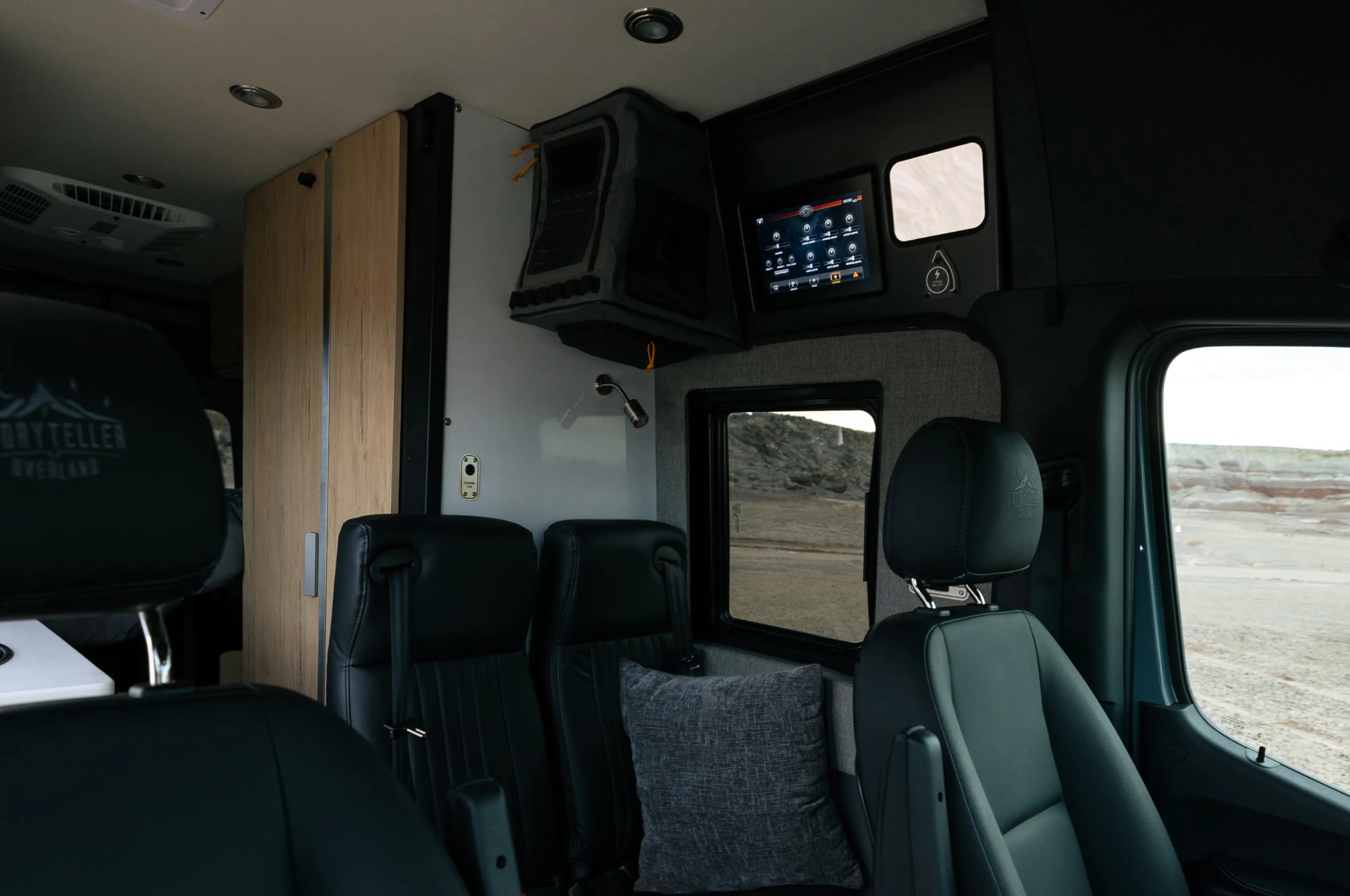 Modern camper van interior with leather seats, swivel chair, control panel, and adventure van window view