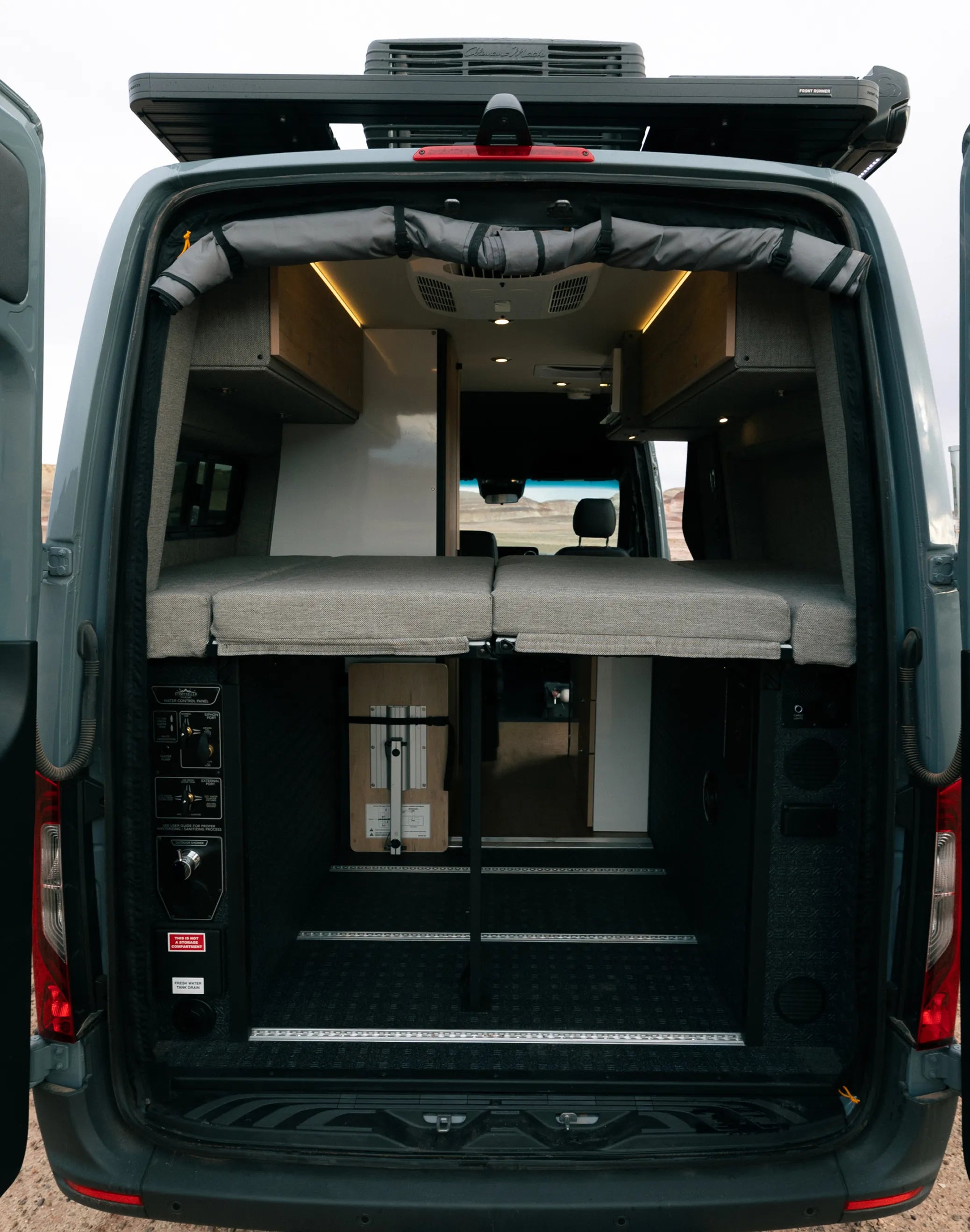 Rear interior of adventure van with raised bed, storage space, and custom camper van build.