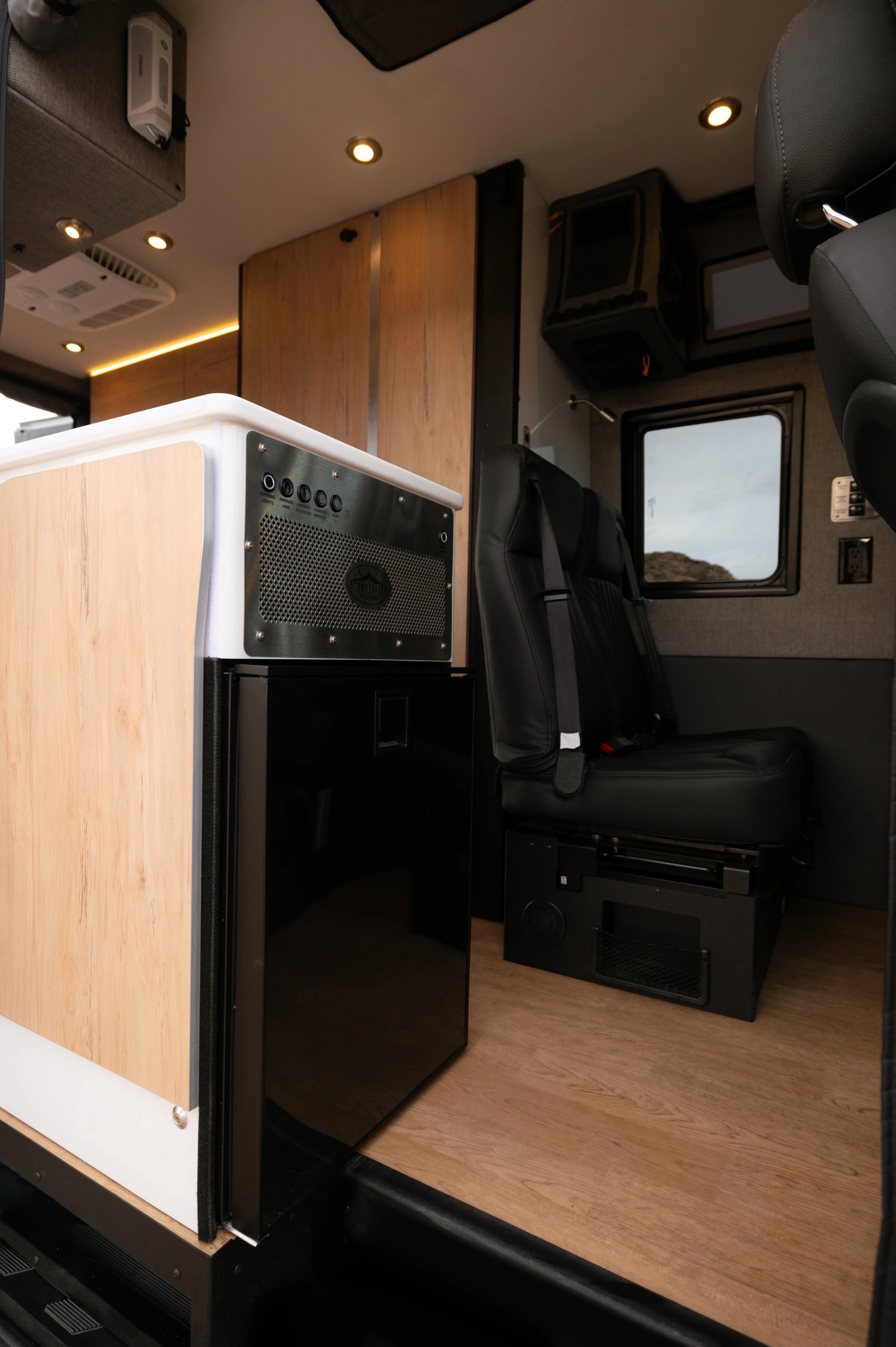 Modern interior of adventure van with rear seats, built-in heater, and wood cabinetry, ideal for vanlife or overlanding.
