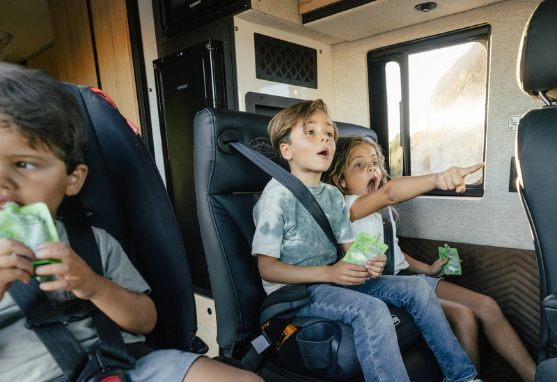Kids in seatbelts enjoying a road trip inside adventure van, campervan, Class B RV interior