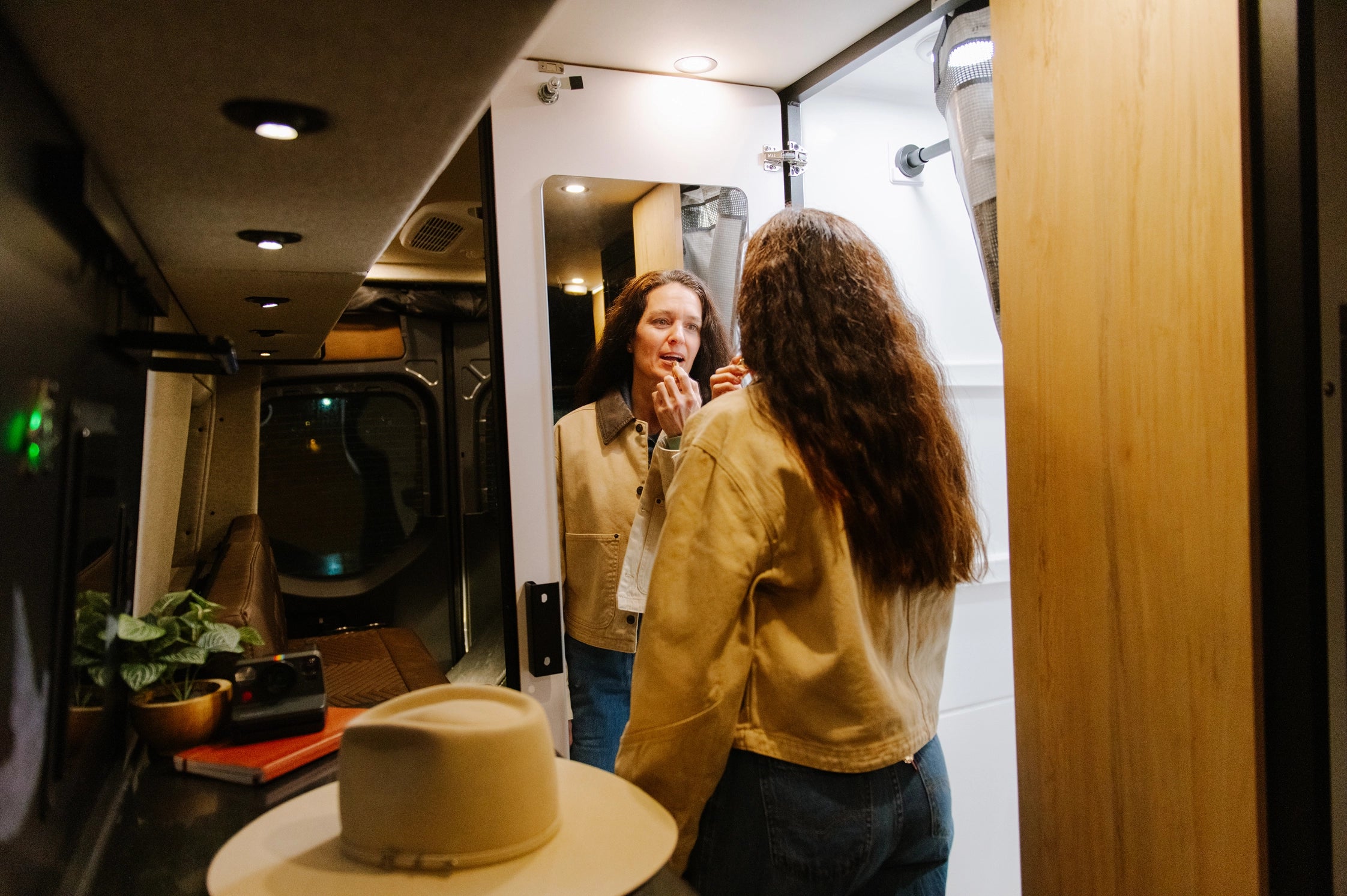 Woman using mirror in adventure van interior, ideal for campervan, van life, overlanding.