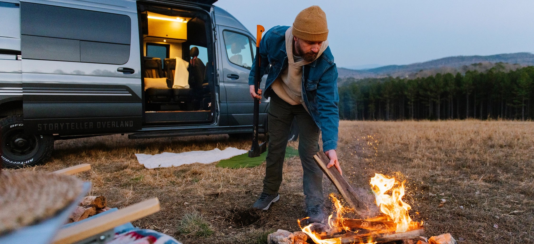 Camper van adventure rig parked outdoors with man building campfire, ideal for vanlife and overlanding
