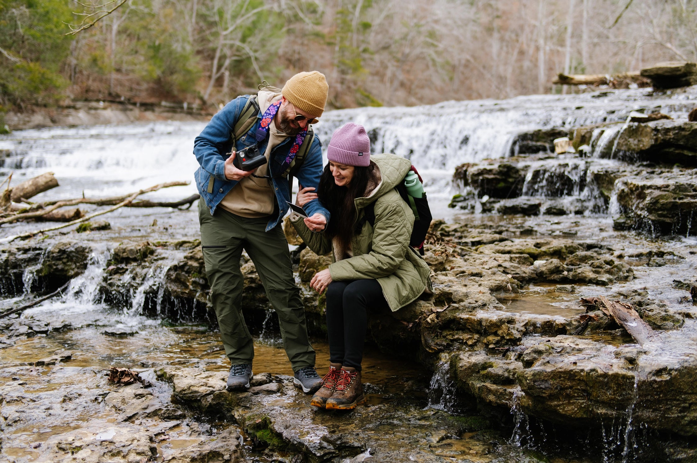 Couple hiking by a waterfall, enjoying adventure travel and outdoor exploration for vanlife nomads
