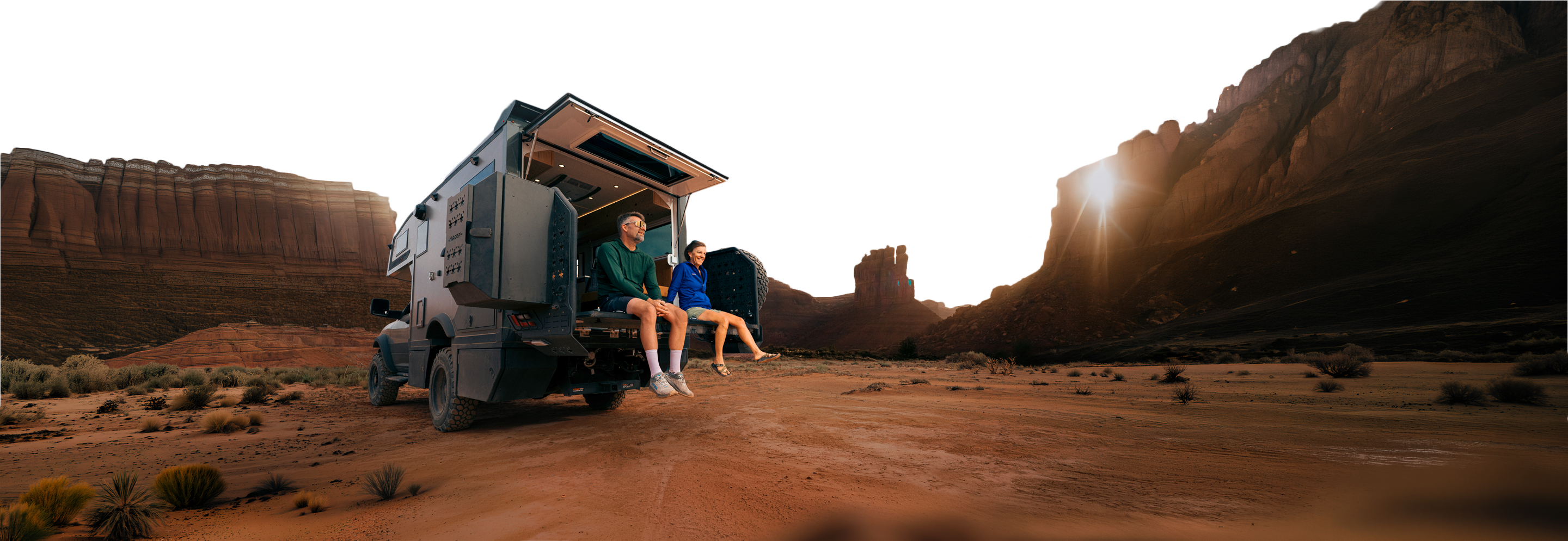 Two people sitting FlipOut Deck in a desert landscape with mountains and a sunset.