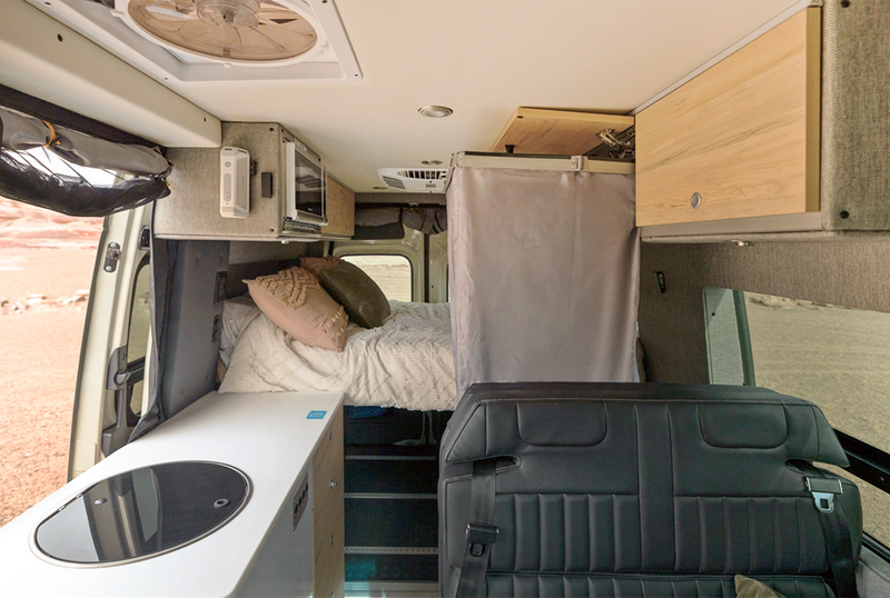 Interior of a luxury camper van with bed, kitchenette, and modular storage for van life adventure
