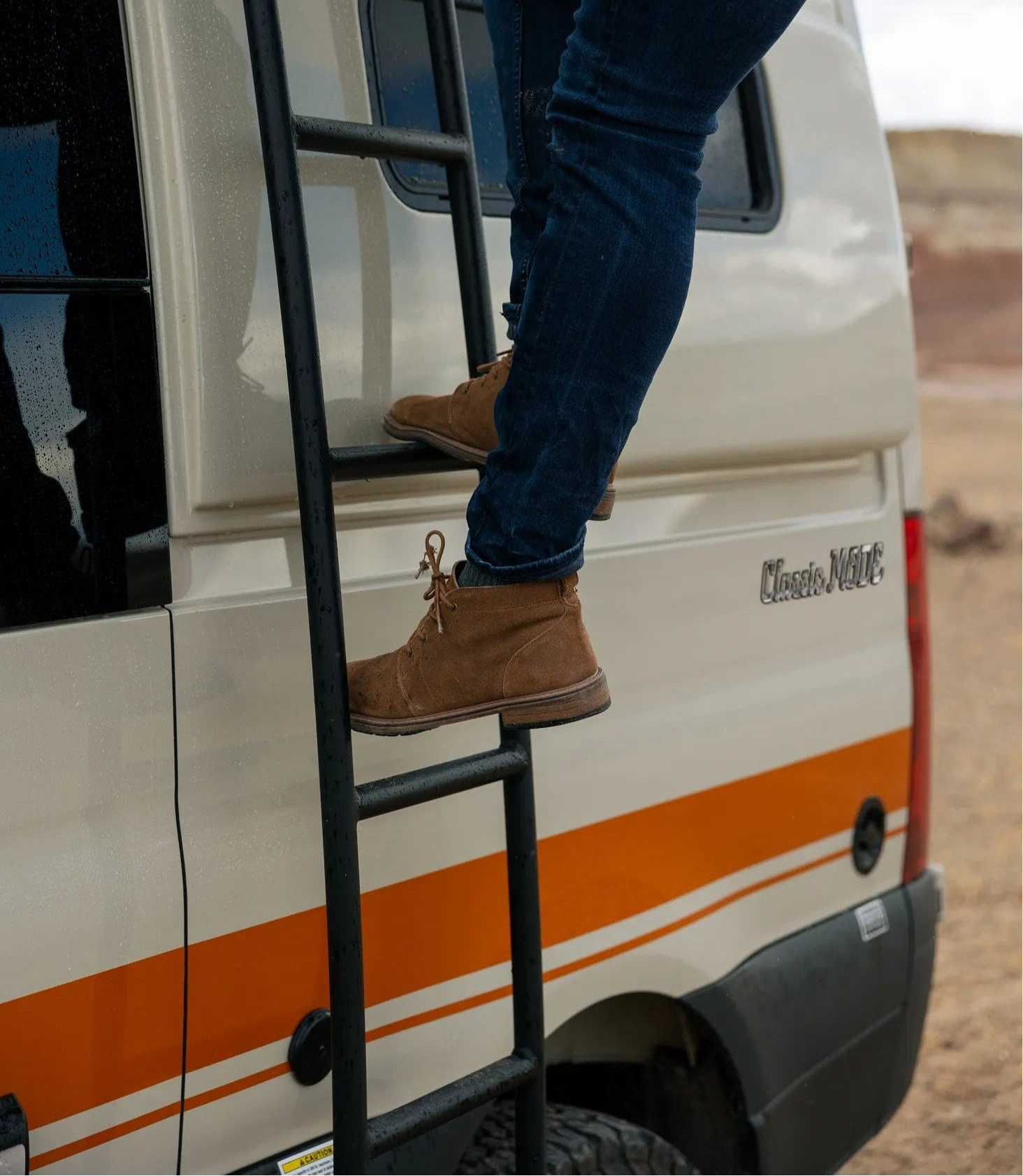Person climbing exterior ladder on Classic MODE camper van, adventure van, overland vehicle
