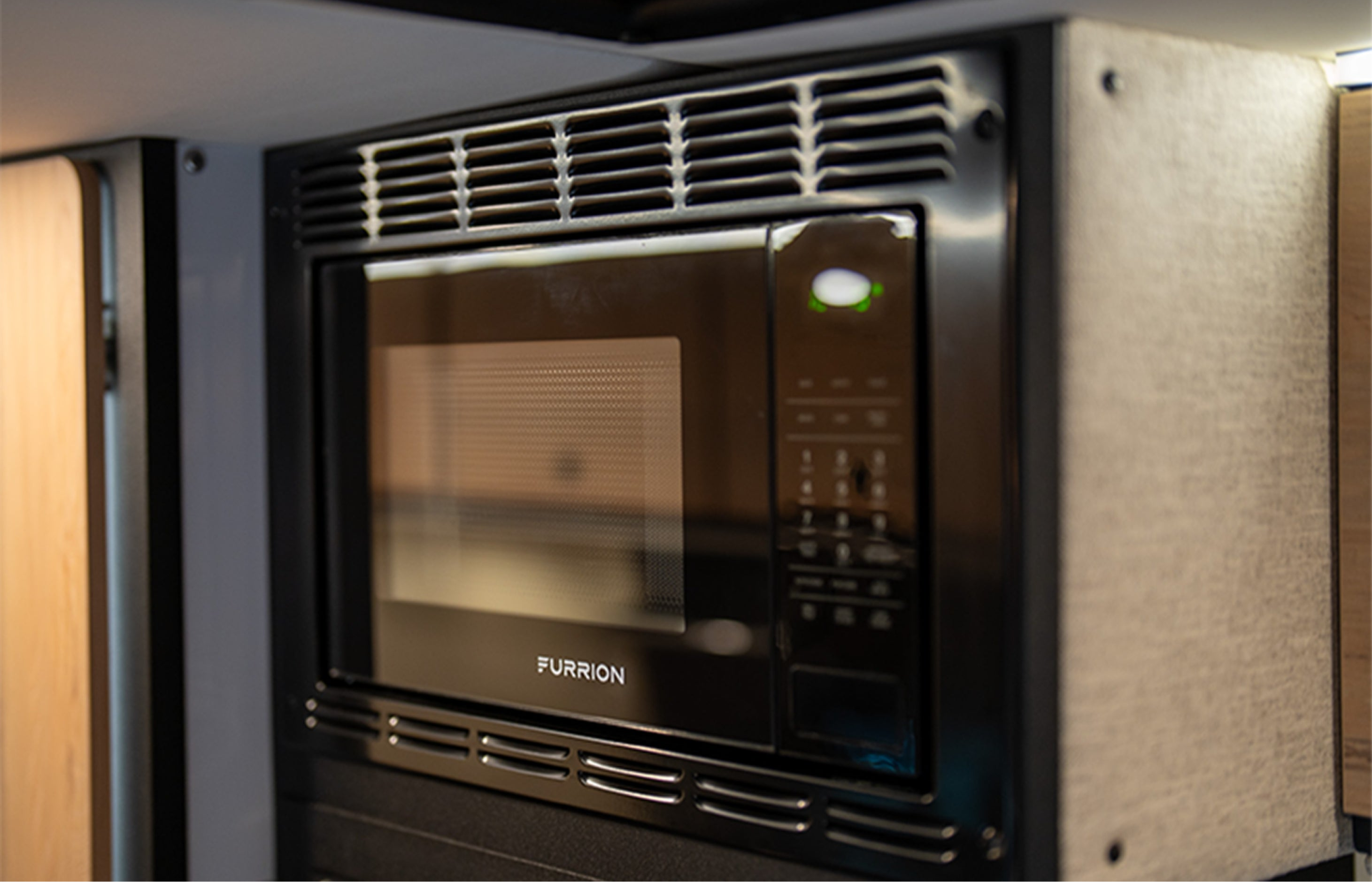 Microwave in camper van kitchen interior, ideal for vanlife, overlanding, and adventure travel.