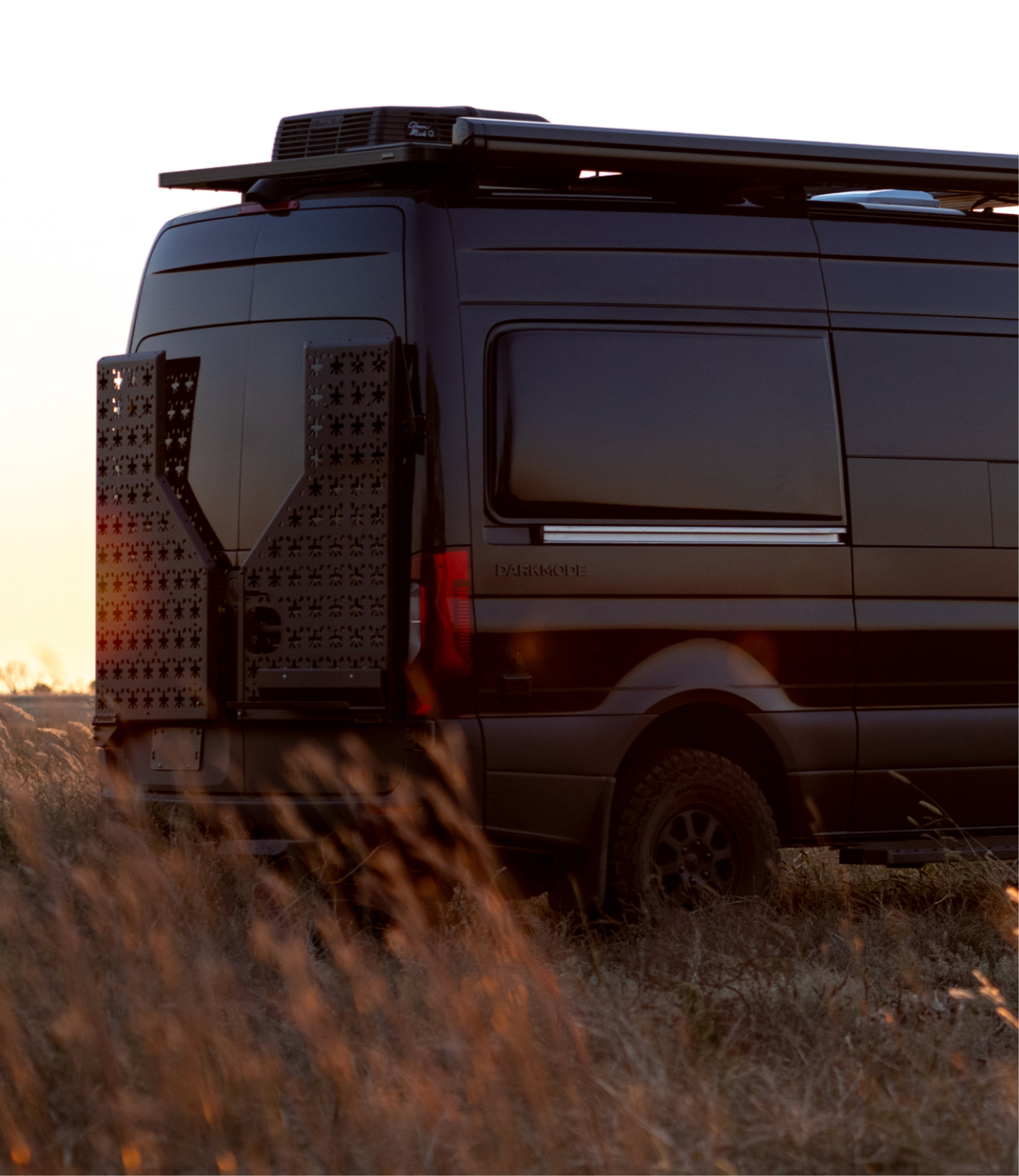 Black offroad camper van exterior side view in grass, Sprinter 4x4 adventure van for vanlife