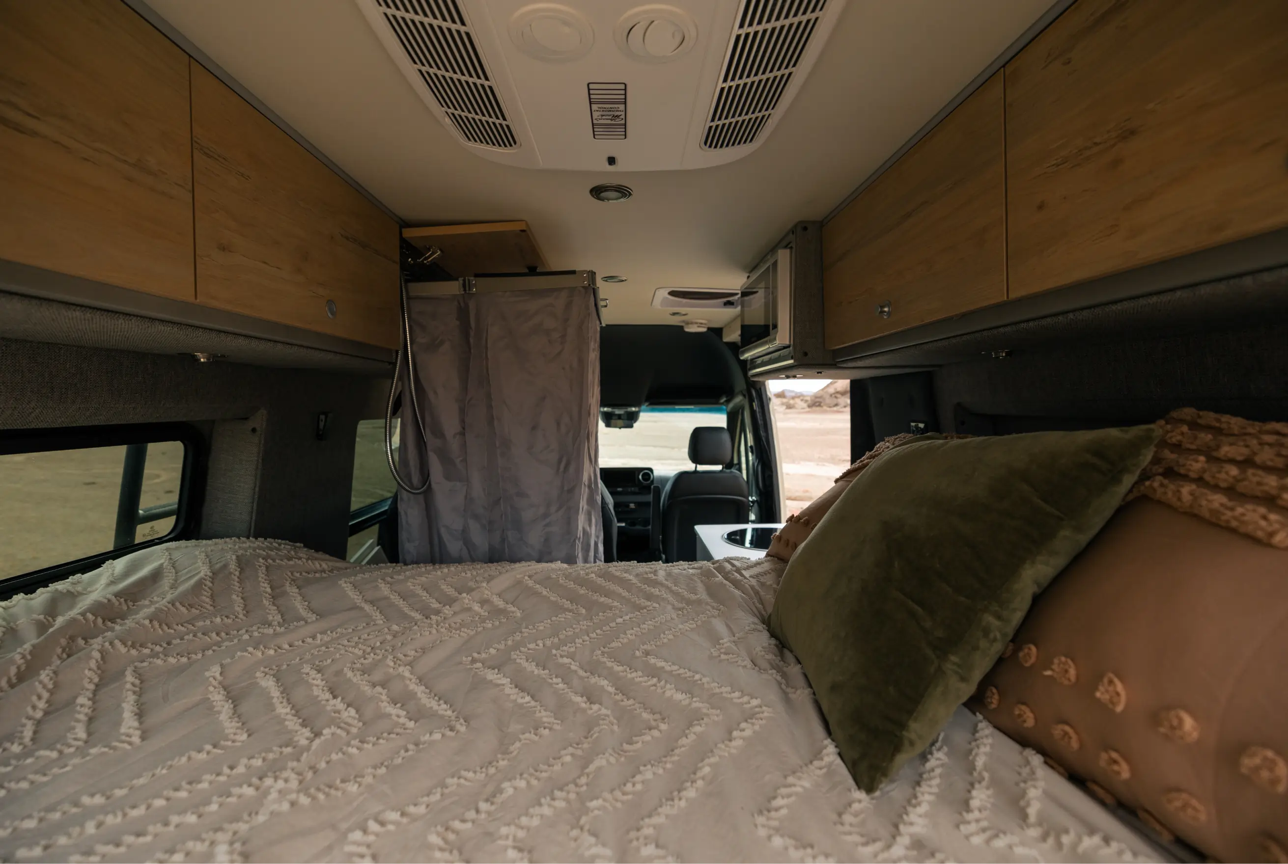 Cozy bed and compact shower inside adventure van, camper van, small motorhome interior