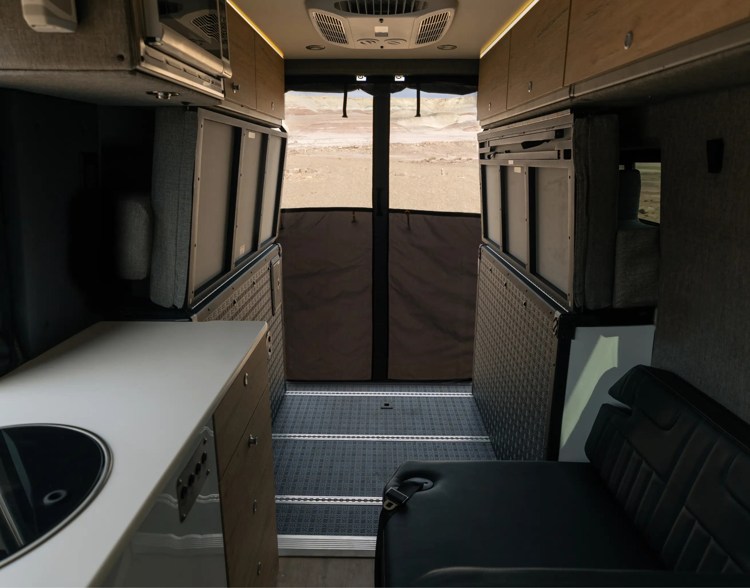 Interior of adventure van with kitchenette, seating and bug screen, ideal for vanlife or overlanding